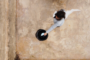 top view of light blue disposable mask discarded in a rubbish bin by a woman
