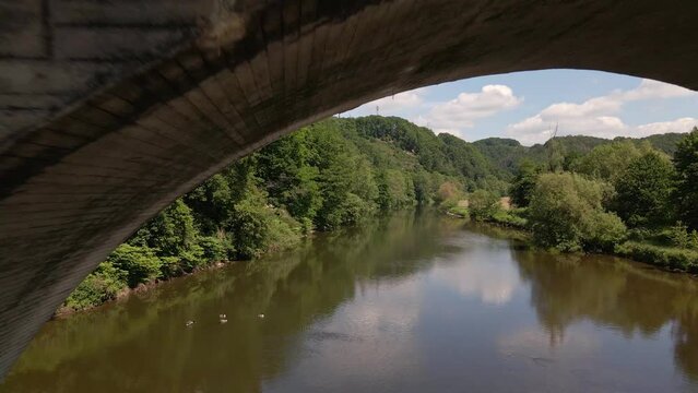 Rusty, old train trestle leading over the Sieg river in west Germany on a sunny spring day. Aerial fly through shot