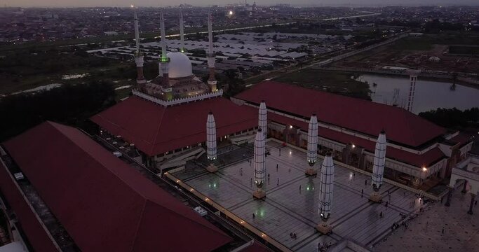 Sliding drone shot of the great Mosque of Central Java (MAJT) in suset time. The light is on. It have some pillars and some umbrela that is closed