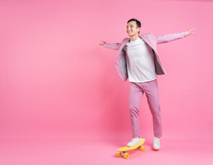 Image of young Asian man playing skateboard on background