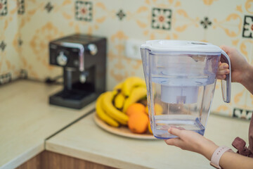 Jug with water filter in hand in the kitchen