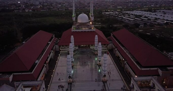Circling close up drone shot of the great Mosque of Central Java (MAJT) in suset time. Th sun is orange and the weather is cloudy. It have some pillars and some umbrela that is closed