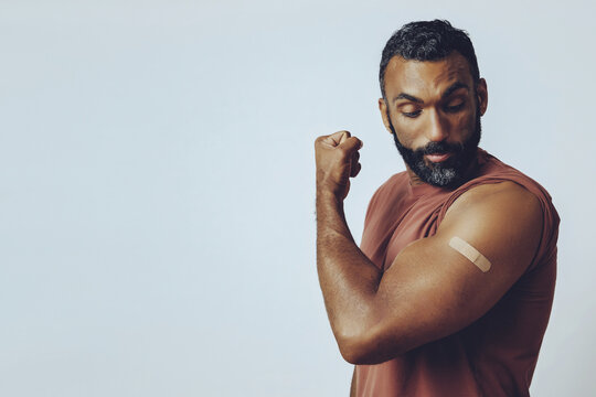 portrait mid adult bearded vaccinated man in the studio flexing arm muscle with plaster studio shot
