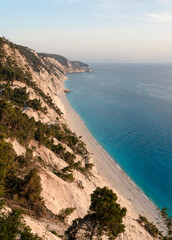 Fototapeta na wymiar Beautiful wild Mediterranean pebble beach under a large massive cliff