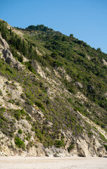 Vertical composition of large rocky hill above the beautiful wild Mediterranean pebble beach