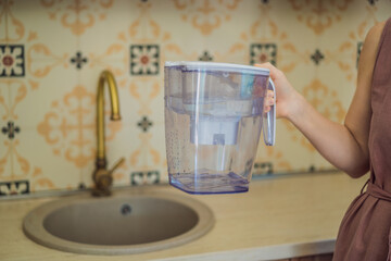 Jug with water filter in hand in the kitchen