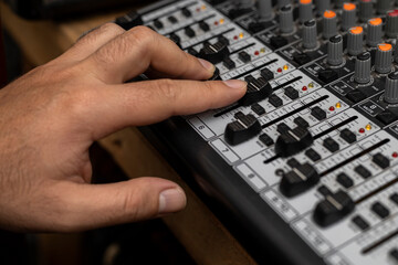 Close-up of a male hand changing volume on mixing board. Creating music, dj concept