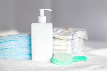 body cream, comb, disposable diaper and diapers on a bed. Baby care. First days of life. Feeding and motherhood