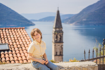 Boy tourist enjoying Colorful street in Old town of Perast on a sunny day, Montenegro. Travel to Montenegro concept. Scenic panorama view of the historic town of Perast at famous Bay of Kotor on a