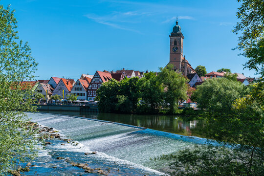 Germany, Nuertingen city and cityscape next to riverside of neckar river water and stadtgarten in summer on sunny day with blue sky, panorama view