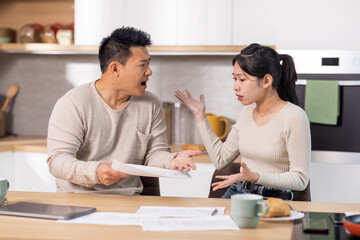 Furious asian man scolding his wife for overspending