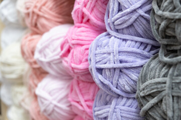 Many multi-colored balls of yarn for knitting on a shelf in a needlework store, close-up, selective focus