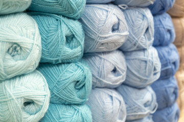 Many multi-colored balls of yarn for knitting on a shelf in a needlework store, close-up, selective focus