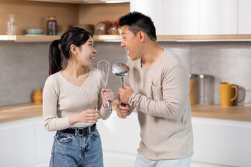 Happy chinese spouses singing while cooking together