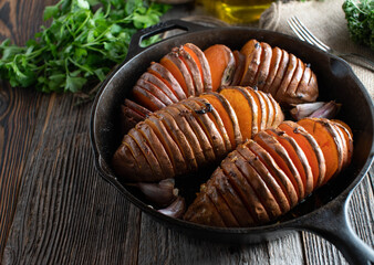 Baked sweet potato with olive oil, garlic, pepper and salt in a cast iron pan