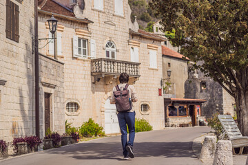 Man tourist enjoying Colorful street in Old town of Perast on a sunny day, Montenegro. Travel to Montenegro concept. Scenic panorama view of the historic town of Perast at famous Bay of Kotor on a