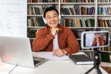 Asian Male Teacher Making Video Lecture Via Phone In Classroom