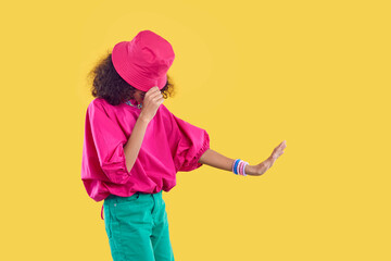 Little kid dancing. Child in trendy outfit posing isolated on solid yellow color fashion studio...