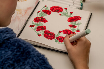 Hand drawing a red poppy wreath sketch in a sketchbook with alcohol based sketch drawing markers....