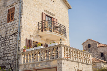 Scenic panorama view of the historic town of Perast at famous Bay of Kotor with blooming flowers on a beautiful sunny day with blue sky and clouds in summer, Montenegro, southern Europe