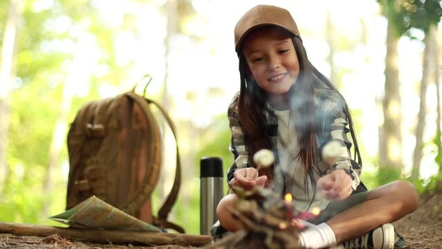 Girl scout frying marshmallows on fire at the woods	