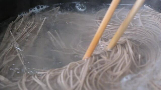 close up cooking buckwheat noodle in hot water. super slow motion