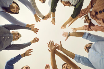 Team of business people reaching up together. Group of young and mature people joining hands, white background, cropped low angle shot, from below bottom view close up. Teamwork, participation concept - obrazy, fototapety, plakaty