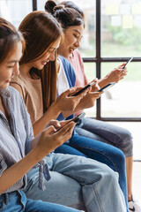 Group of four young Asian female people using smartphones together, modern lifestyle or...