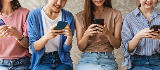 Group of four young Asian female people using smartphones together, modern lifestyle or...