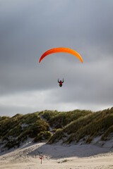 paraglider in the sky over dunes