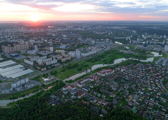 River in city on sunset, aerial view. Suburb houses and multi-storey residential buildings near river in Minsk, Belarus. Cottages and wooden suburb house. Suburban house on sunset panarama, drone view