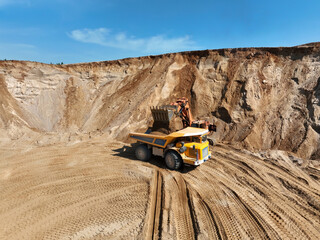 Excavator load sand into mining truck in opencast. Mining excavator in open pit during sand mining....