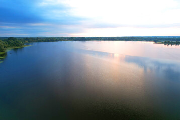 Lake in wild nature, aerial view. Lake on sunset in summer. Aerial panoramic landscape view of lake in wildlife. Drone view of wetland in green colors. Rural environment, clean air and ecology. Pond.