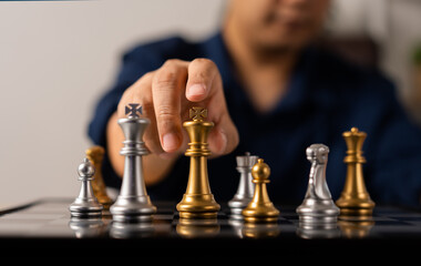 Close up of hands of a business man moving king golden chess to defeat opponent the chess game is development analysis, strategy, and plan, the management or leadership concept.