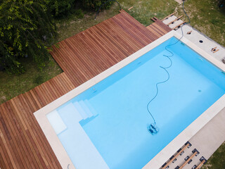 aerial drone flight over beautiful green garden with pool and the wooden deck of the pool is in...