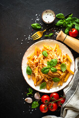 Italian pasta with tomato sauce, basil and parmesan cheese on dark table.