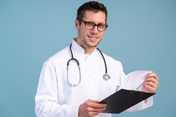 Young doctor wearing glasses, white coat and stethoscope holding folder with a report in his hand. Medicine concept