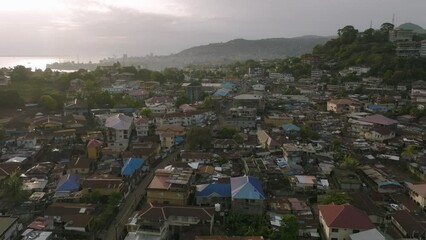 Fast aerial flyover of downtown Freetown, Sierra Leone during the sunrise with morning traffic.