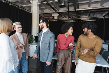 cheerful multiethnic business people talking and gesturing in advertising agency.