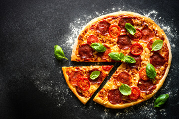 Traditional italian pizza with salami cheese, tomatoes and basil.