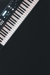 Piano keys, synthesizer on a black background, flat lay.
