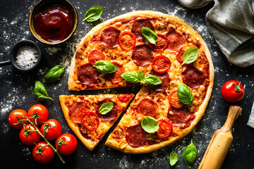 Traditional italian pizza with salami cheese, tomatoes and basil.