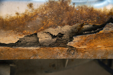 Deep rust on the body of a gray old car. Rust and corrosion hole on old worn out painted metal surface. Body parts repair. Need for repair.