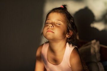 Child girl 4 years old enjoys the sun rays indoors, vitamin d and joy