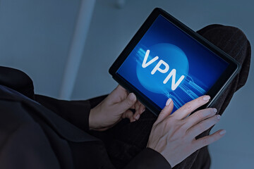 Neon digital blue Bitcoin theme with a young woman holding a tablet computer in the office. Studying cryptocurrencies