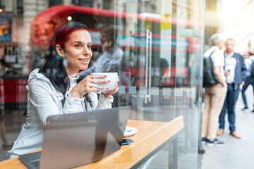 Young business woman drinking coffee in a cafe in the city - 512389077