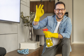 Young man in yellow gloves using cleaner