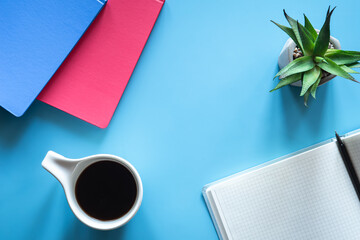 A cup of coffee and notepads on a blue background, minimalism.