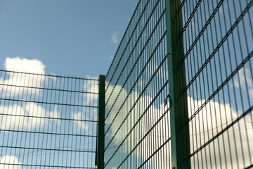 Fototapeta na wymiar Green fence. Steel mesh on sports field.