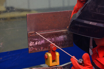 welder holding an electrode holder welding metal pieces at a workshop